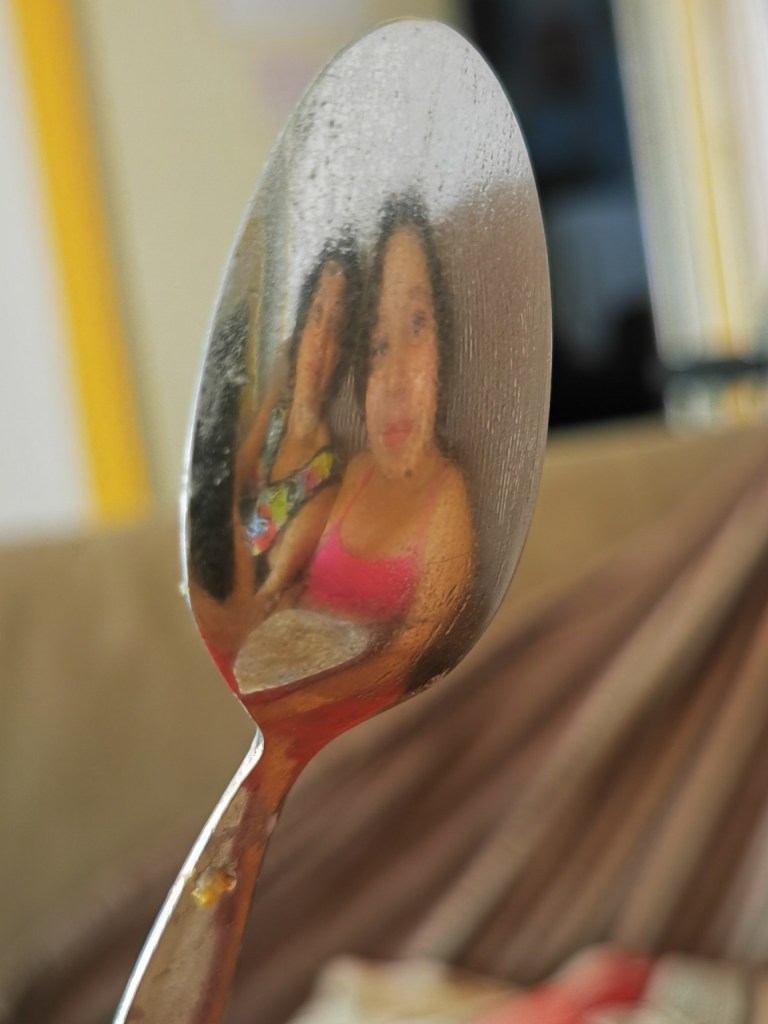 Reflejo dos rostros en la superficie de una cuchara metálica